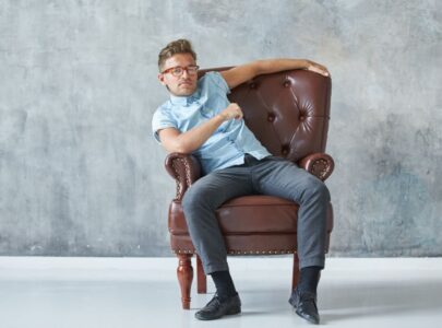 short man sitting on a brown leather chair
